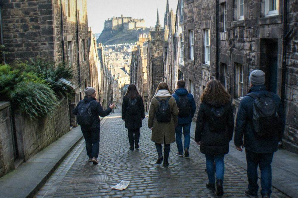 Stone tenement walls rising above a steep cobbled close in Edinburgh's Old Town