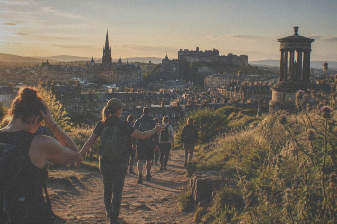 Edinburgh's Old Town rooftops and a church spire seen from a green hillside path