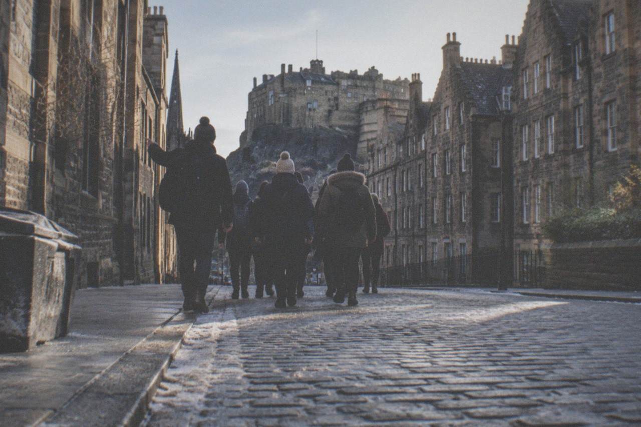 Cobbled Royal Mile street with tall stone tenement buildings on both sides