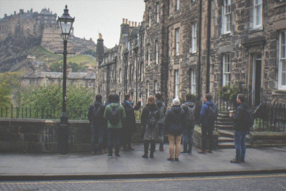 A guide speaking to a small standing group on a cobbled Edinburgh close