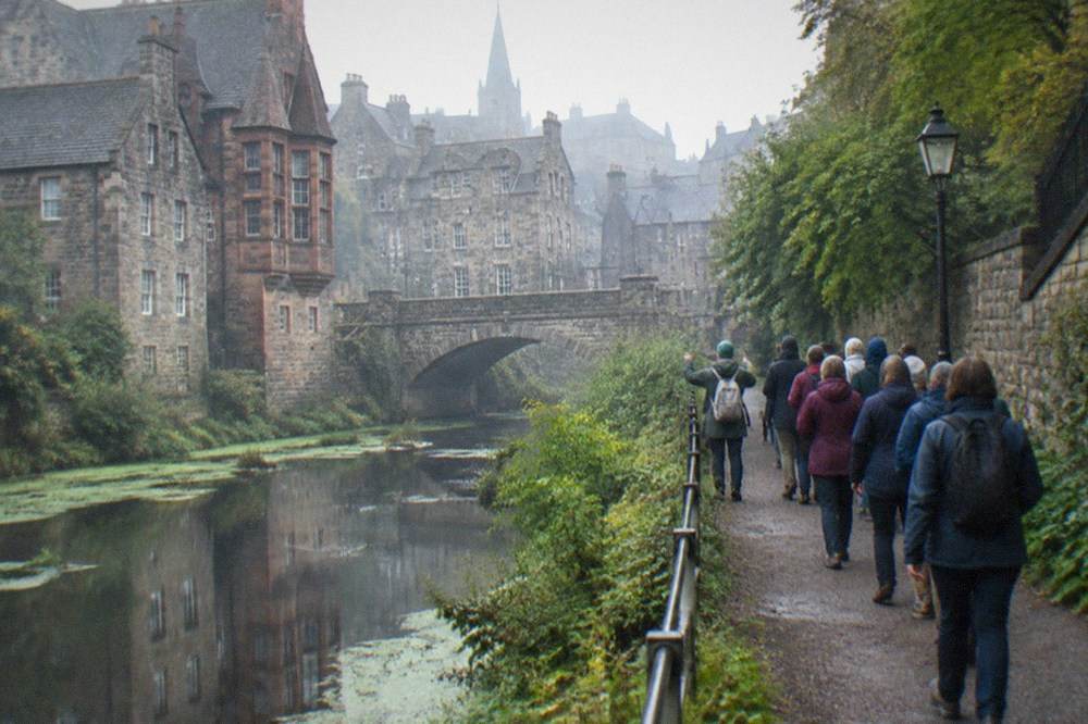 Old stone buildings and a footbridge above a river running through a quiet valley village