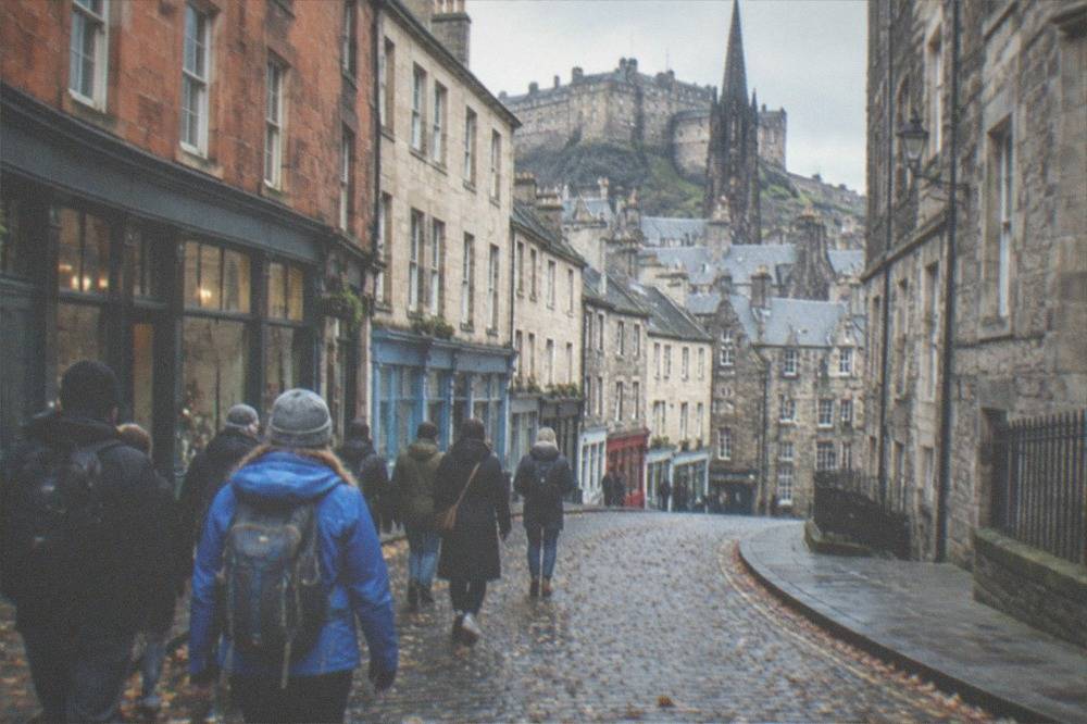 A steep narrow cobbled close between tall old stone tenement buildings in Edinburgh