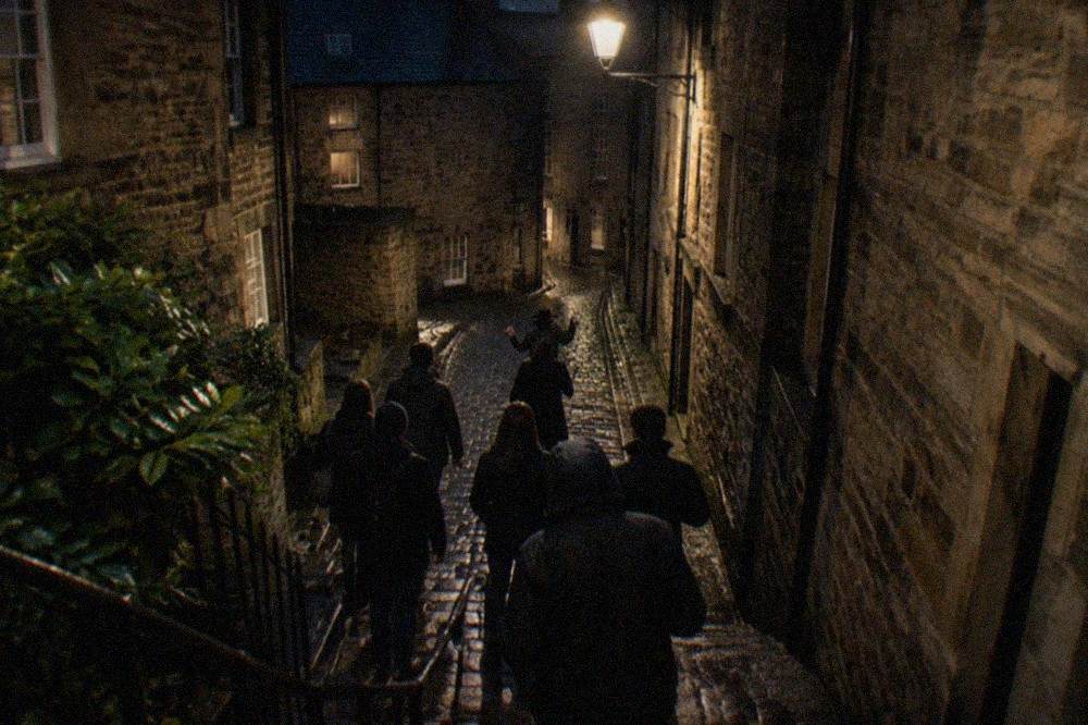 A narrow stone close in Edinburgh lit by a single lamp at night