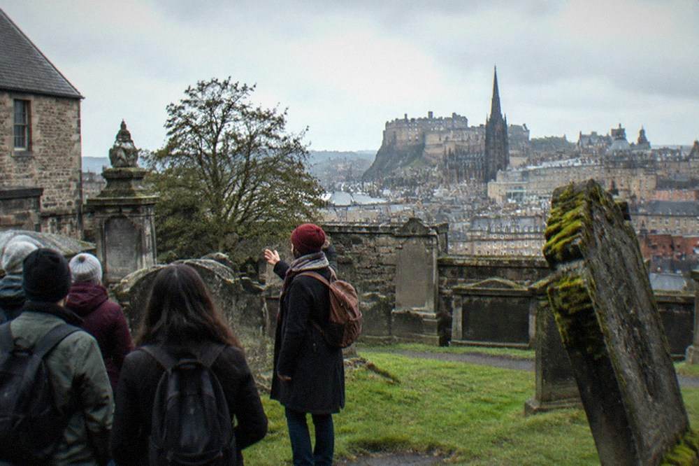 Greyfriars Kirkyard gravestones under a grey sky with the Edinburgh skyline behind