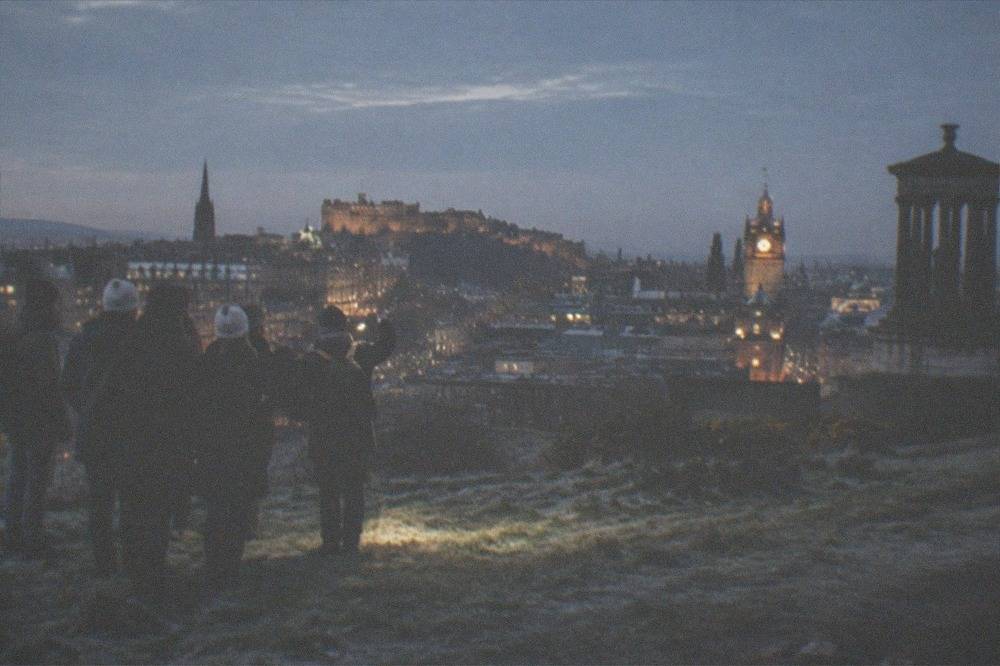 Edinburgh city skyline and castle silhouetted against a night sky from a hill