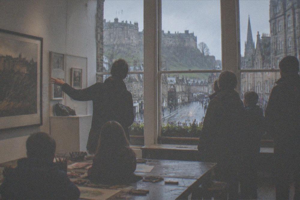 Museum gallery interior with children's activity tables and large windows onto a rainy street
