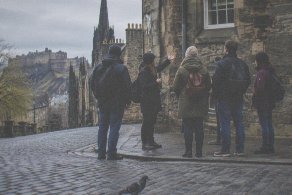 Tour group gathered around a guide near Edinburgh Castle esplanade
