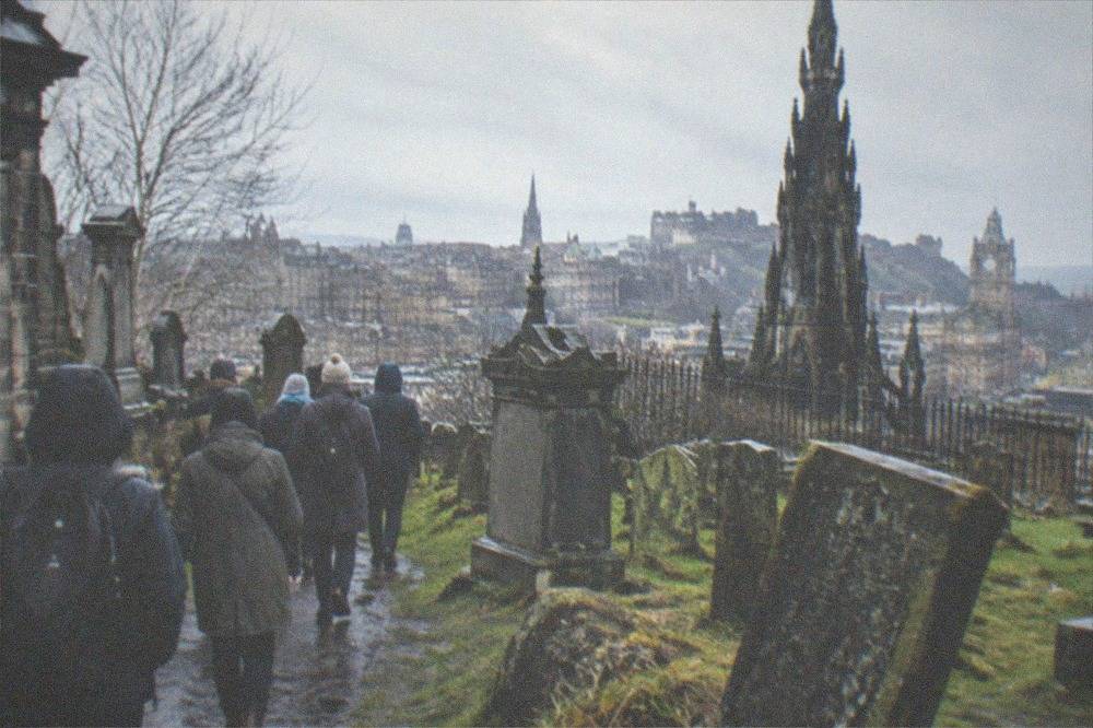 Old cemetery with weathered grey gravestones and a church spire behind